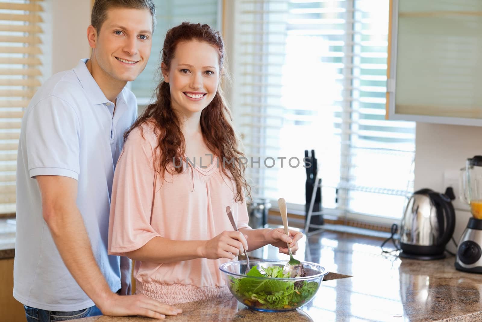 Young couple with salad in the kitchen