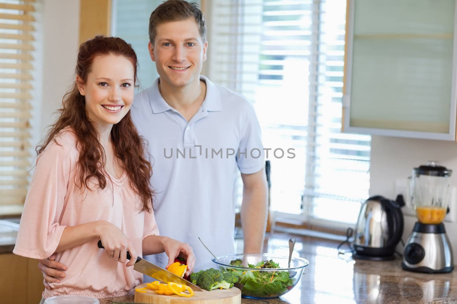 Smiling couple in the kitchen preparing salad