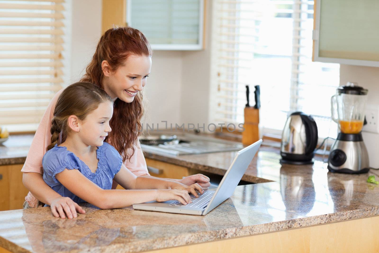 Mother and daughter together with laptop in the kitchen
