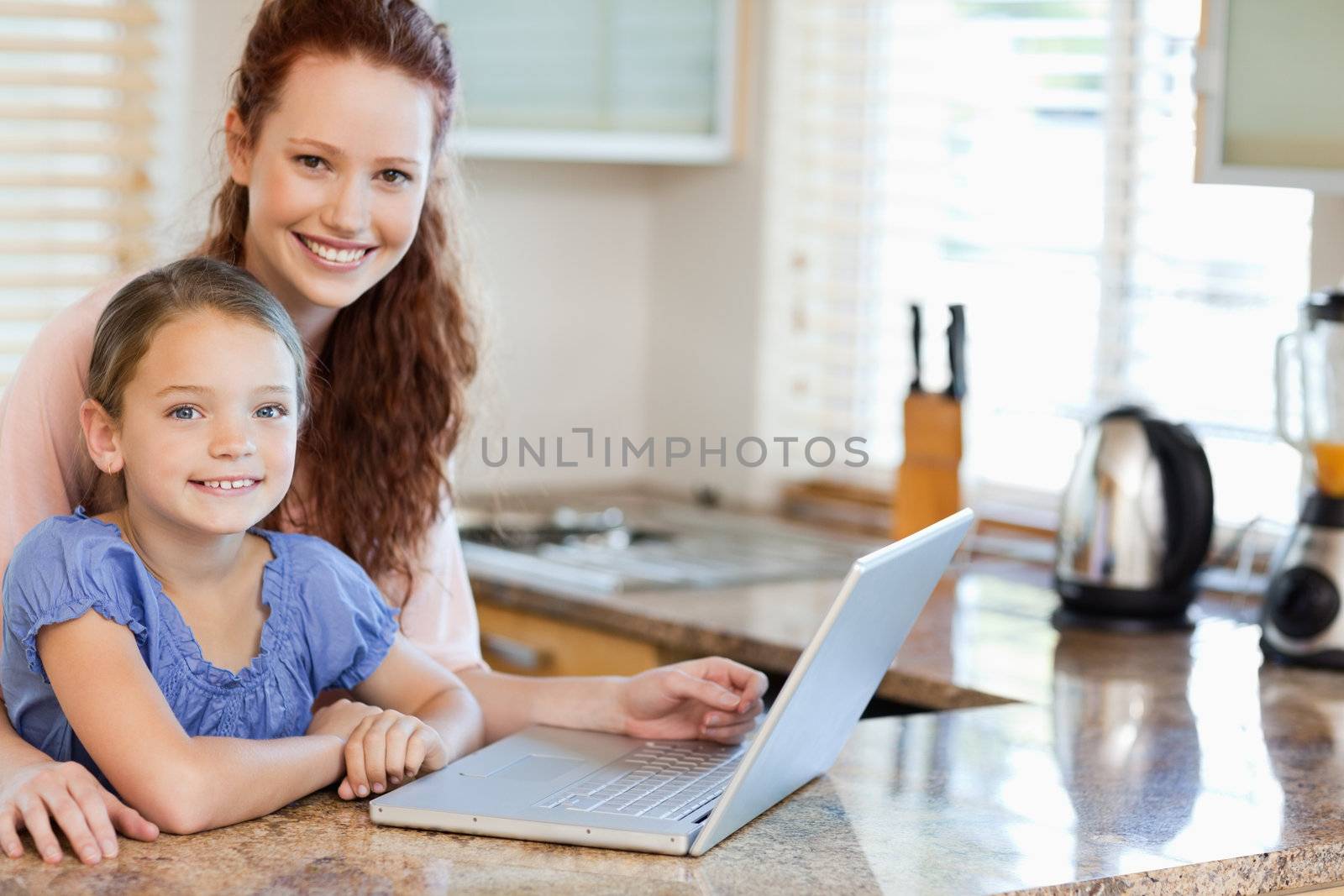 Mother and daughter surfing the internet together in the kitchen