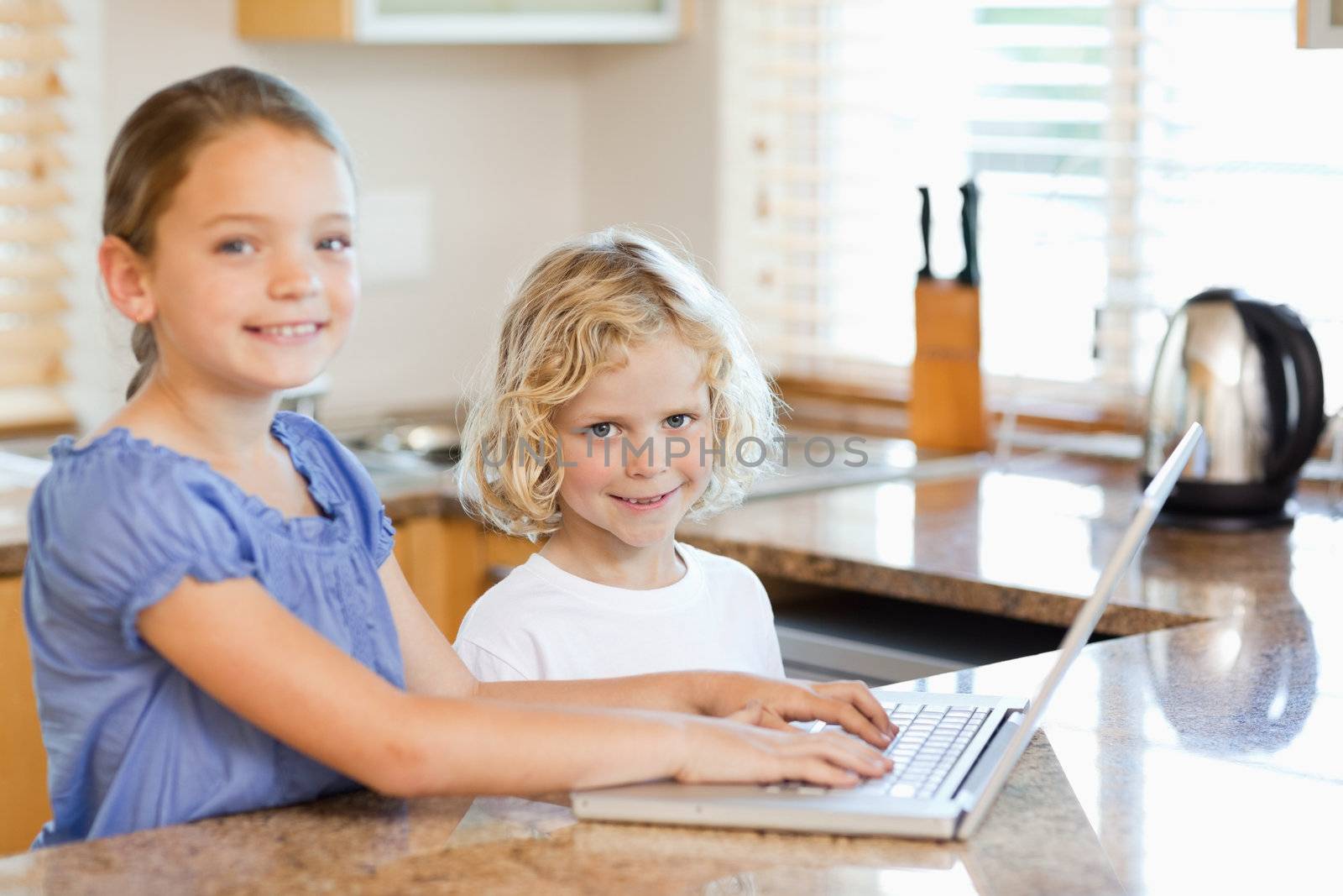Smiling siblings together on the laptop in the kitchen