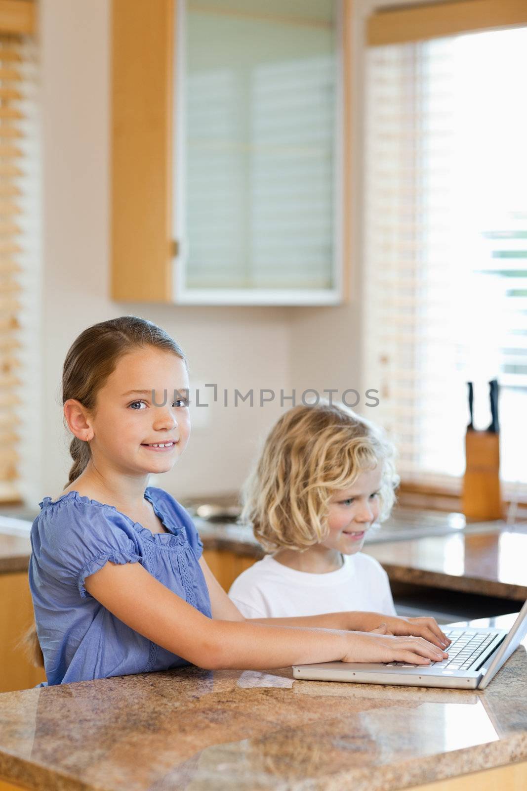 Brother and sister together with laptop in the kitchen