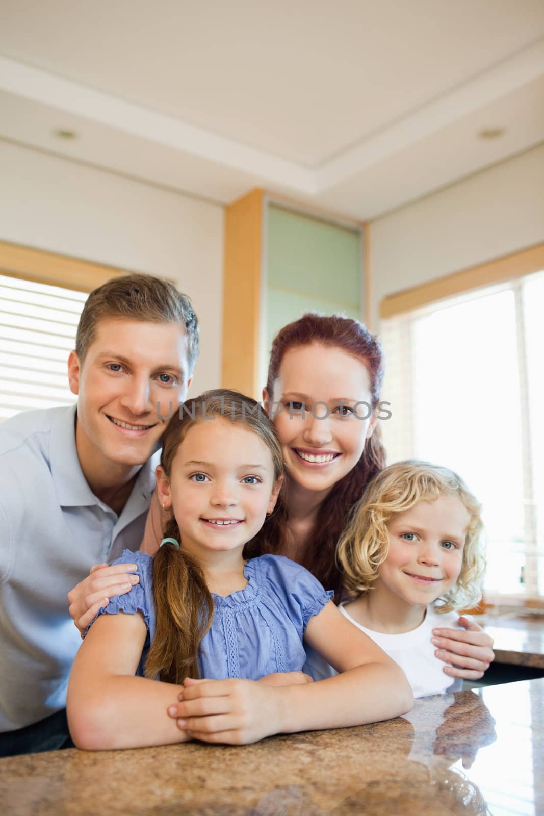 Happy family standing behind the kitchen counter by Wavebreakmedia