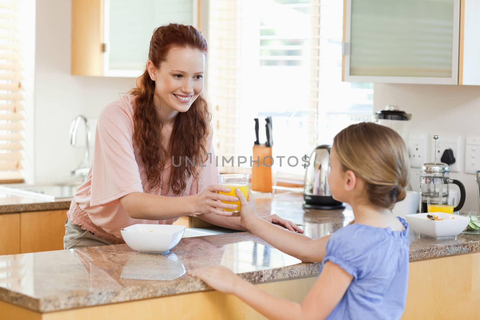 Mother giving her daughter a glass of orange juice