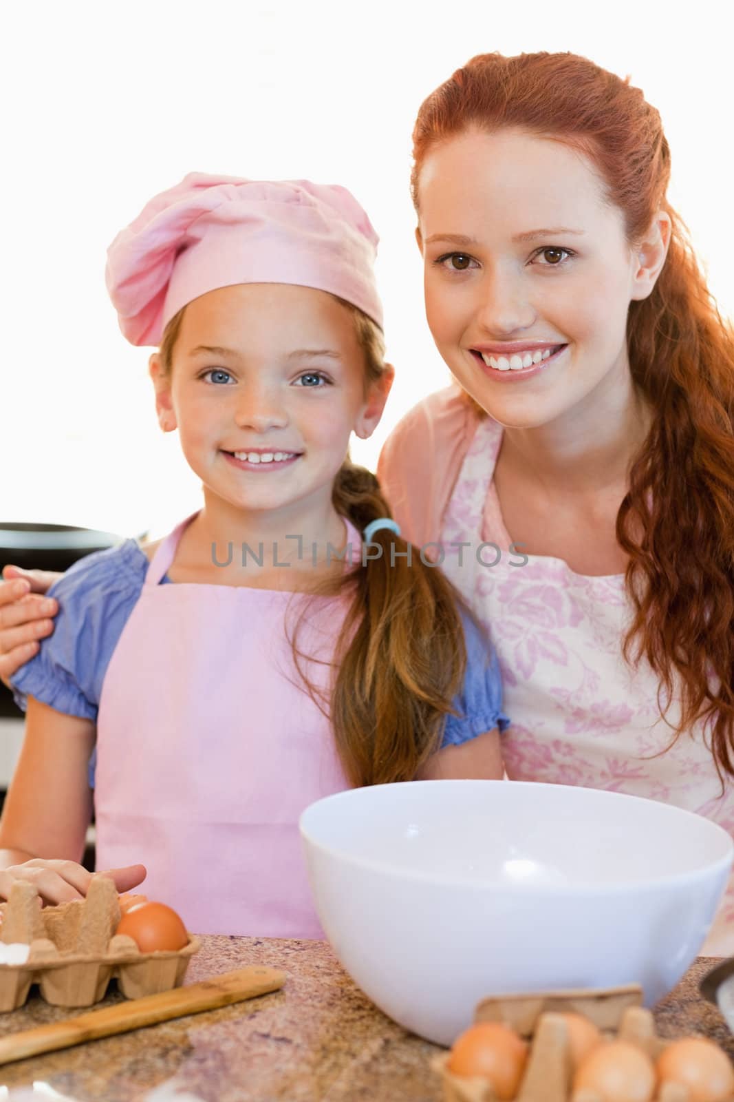 Smiling mother and daughter with ingredients for cookies