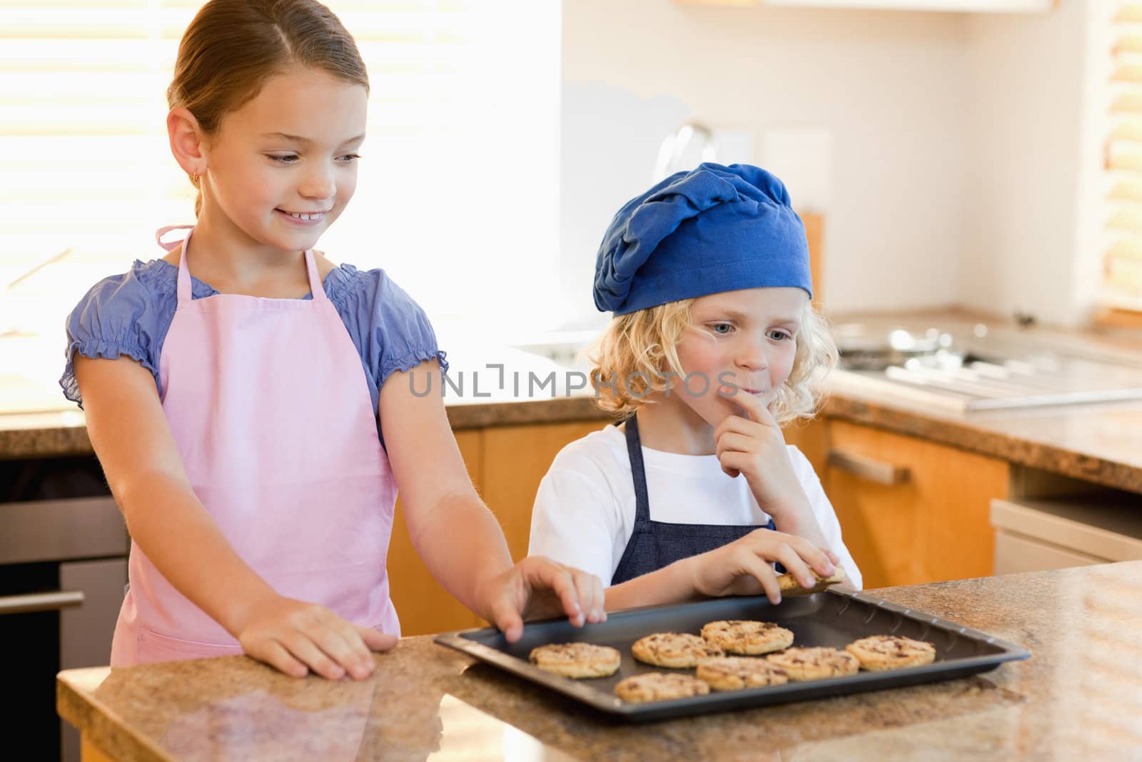 Siblings stealing cookies off the kitchen counter