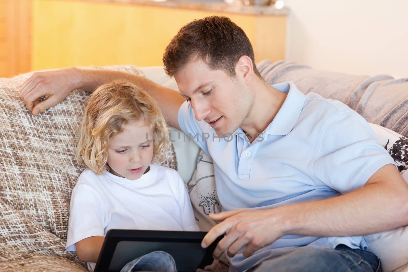 Father and son using tablet on the sofa together