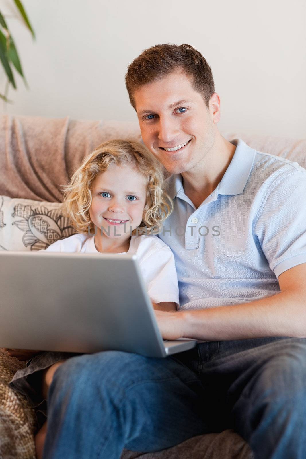 Father and son using laptop on the sofa