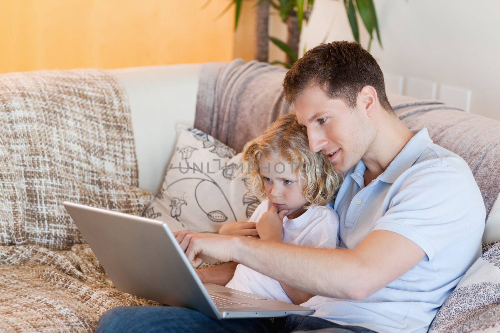 Father explaining his son the internet on the sofa