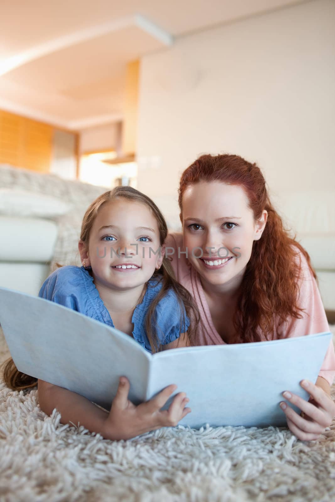 Mother and daughter with magazine on the the floor by Wavebreakmedia