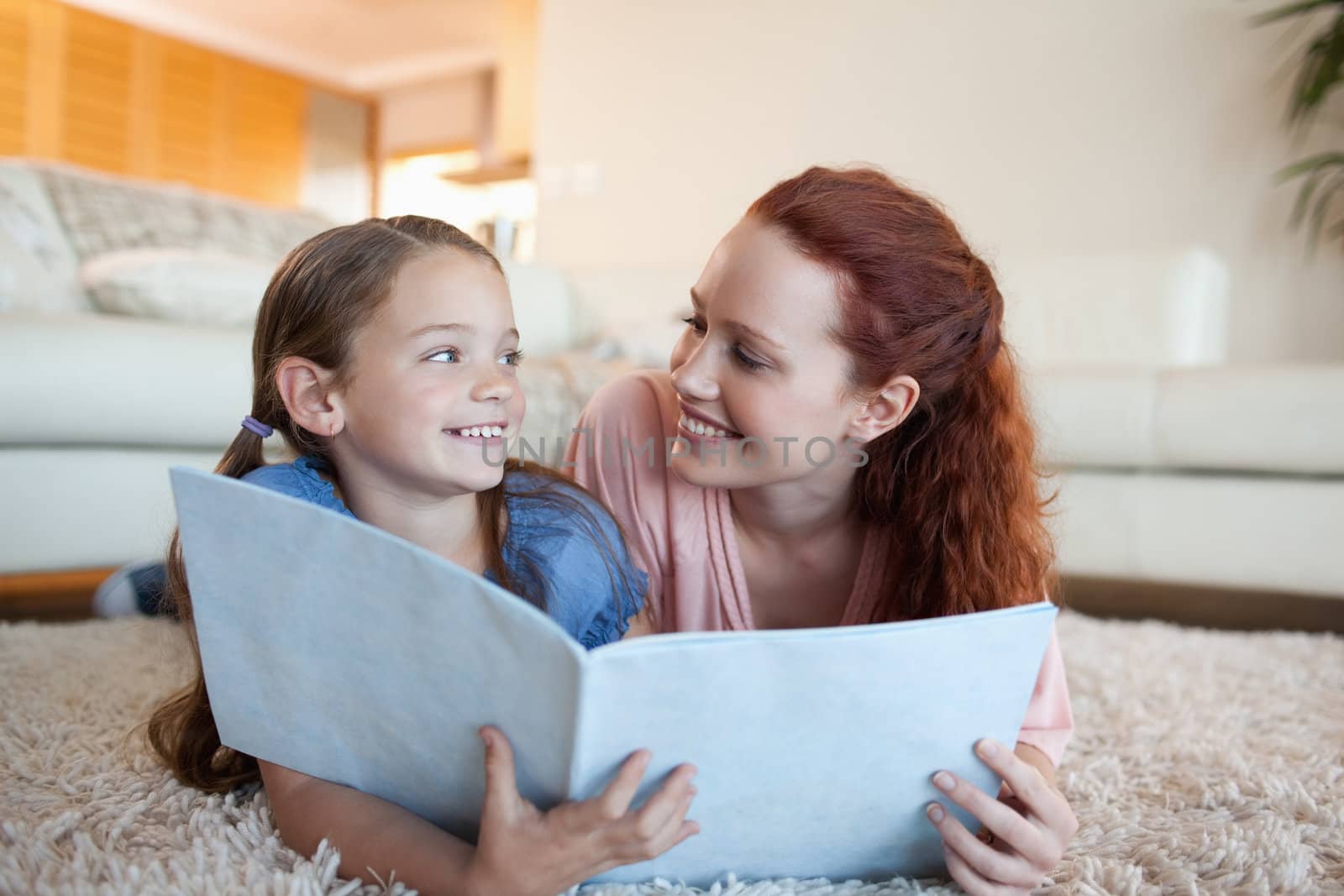Mother and daughter together with periodical on the floor