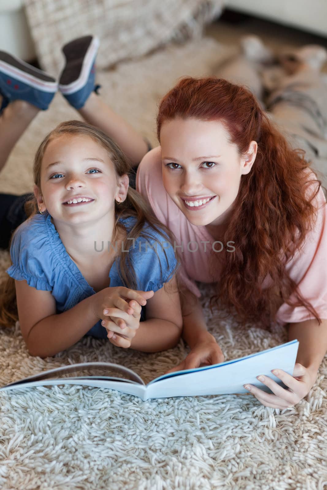 Mother and daughter on the floor reading by Wavebreakmedia