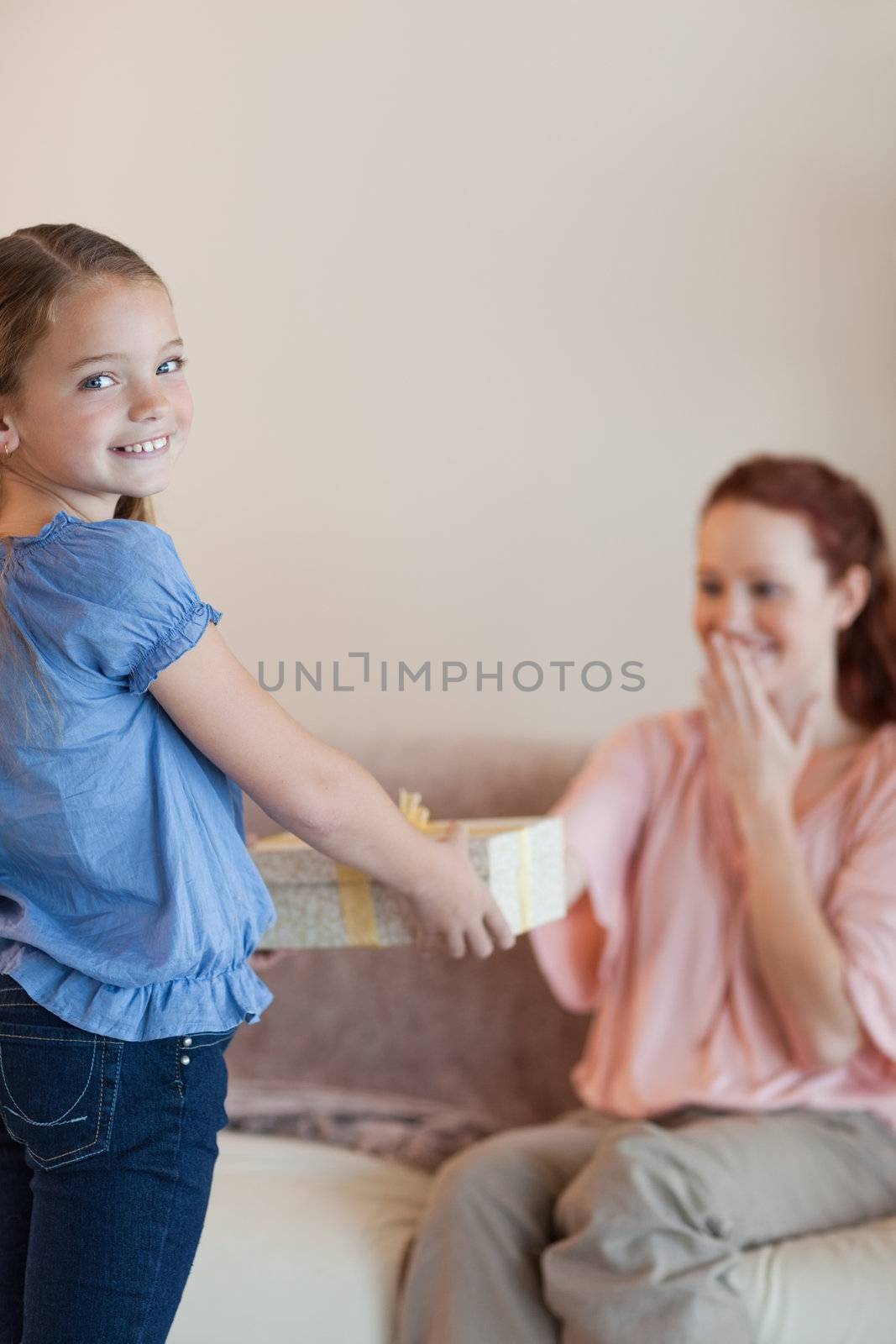 Little girl giving her surprised mother a present