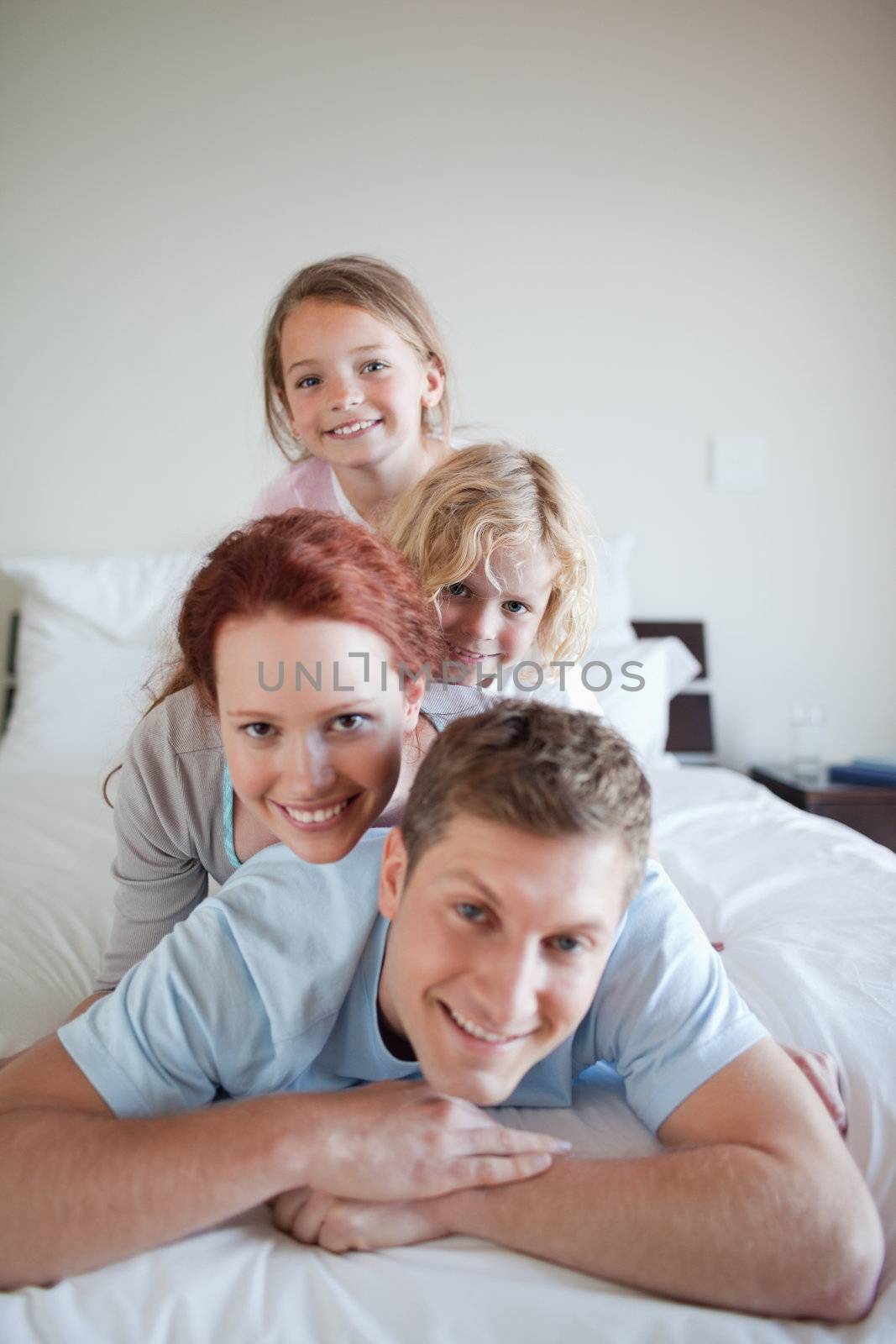 Playful family lying on each other on the bed