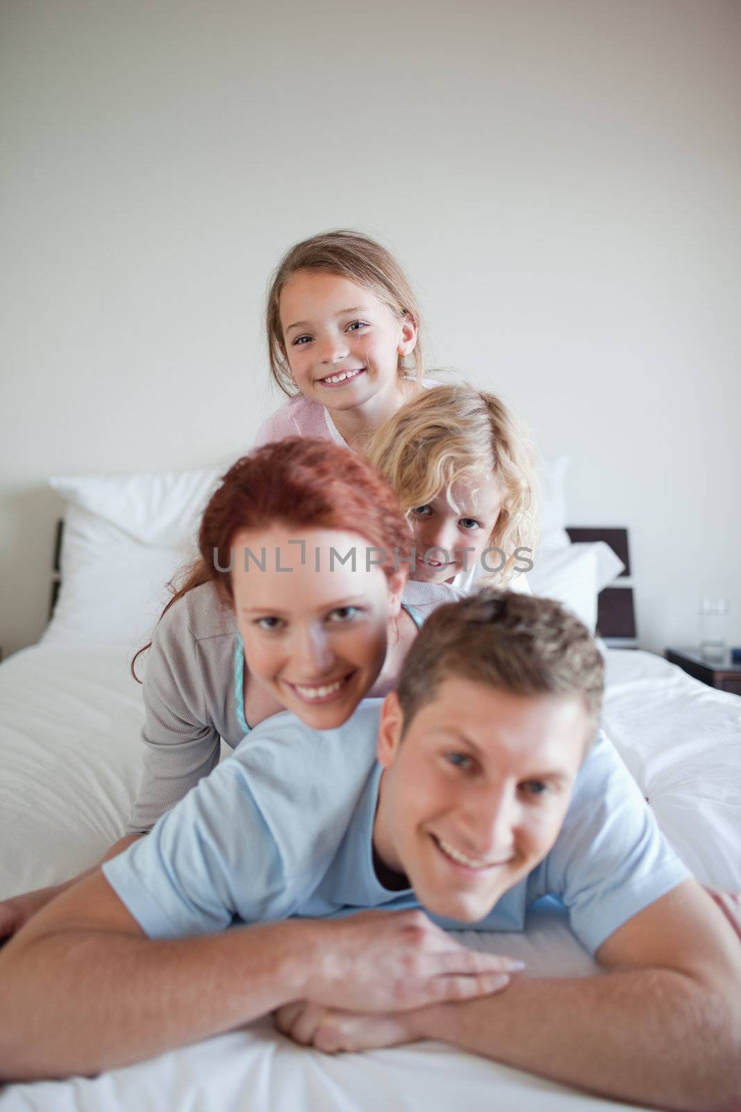 Cheerful family lying on each other on the bed