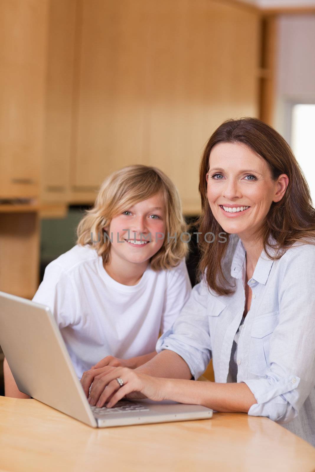 Mother and her son with laptop in the kitchen
