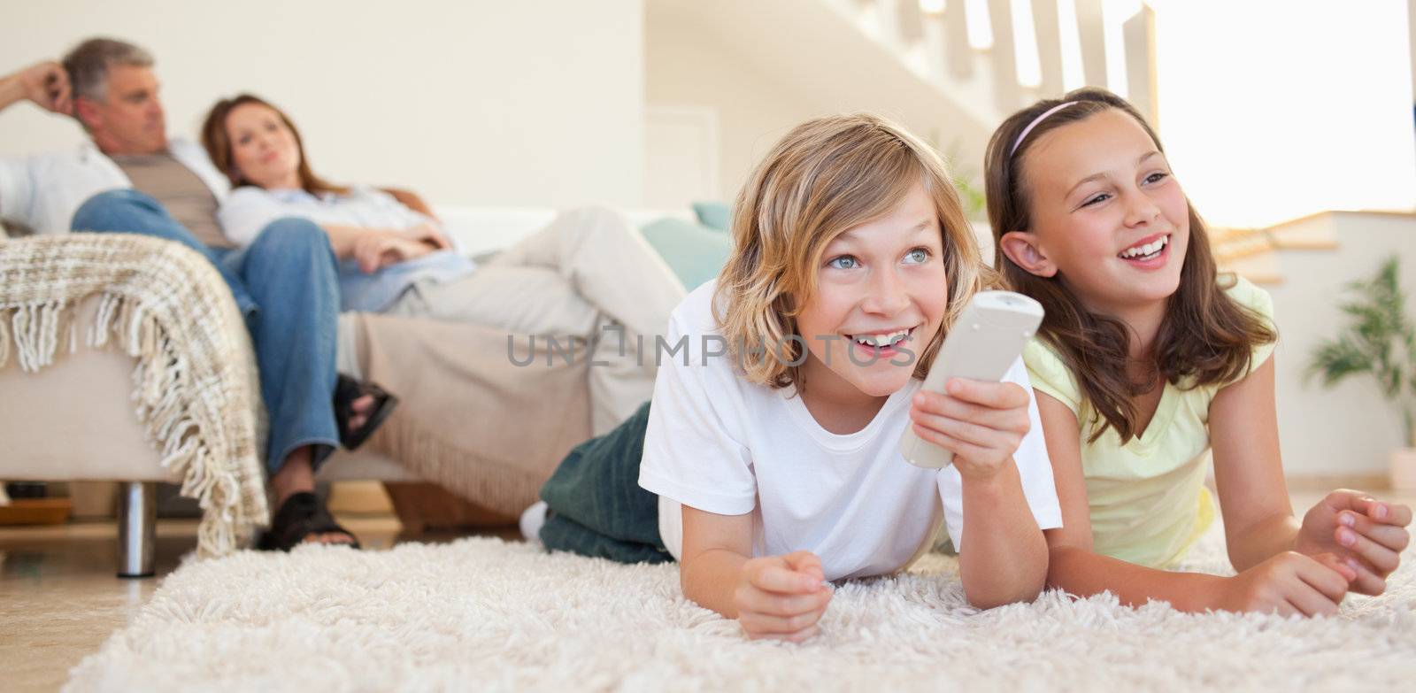 Siblings lying on the floor watching tv by Wavebreakmedia