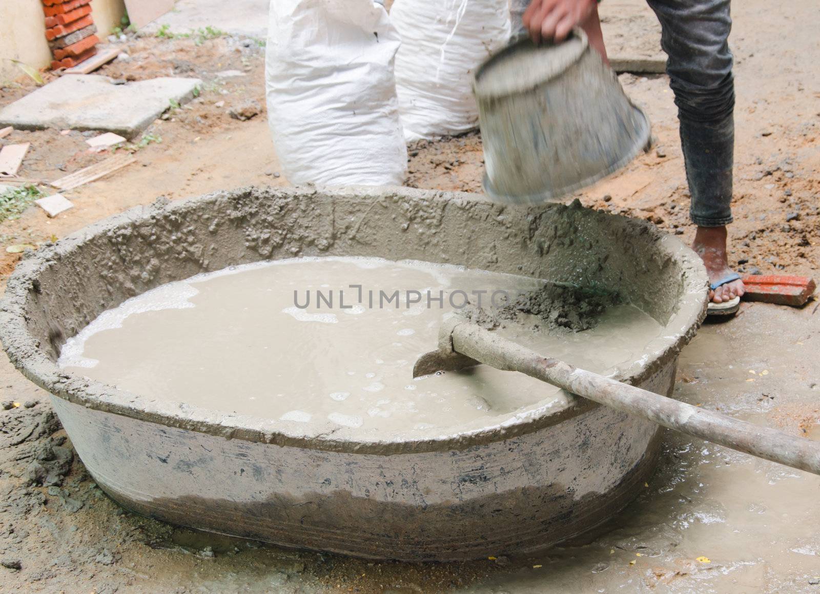 Construction worker mixing cement mortar plaster for interior walls