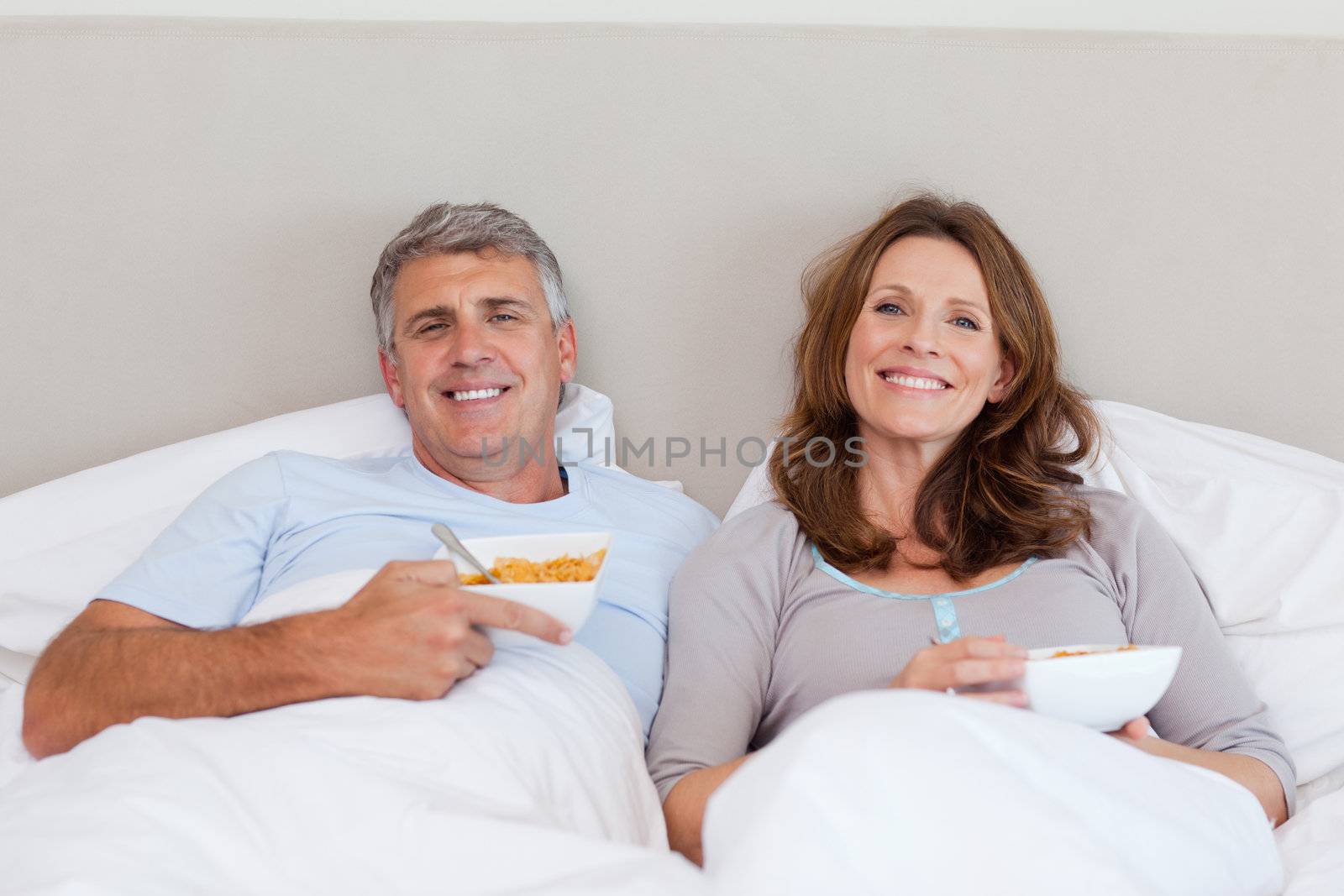 Mature couple eating cereals in bed