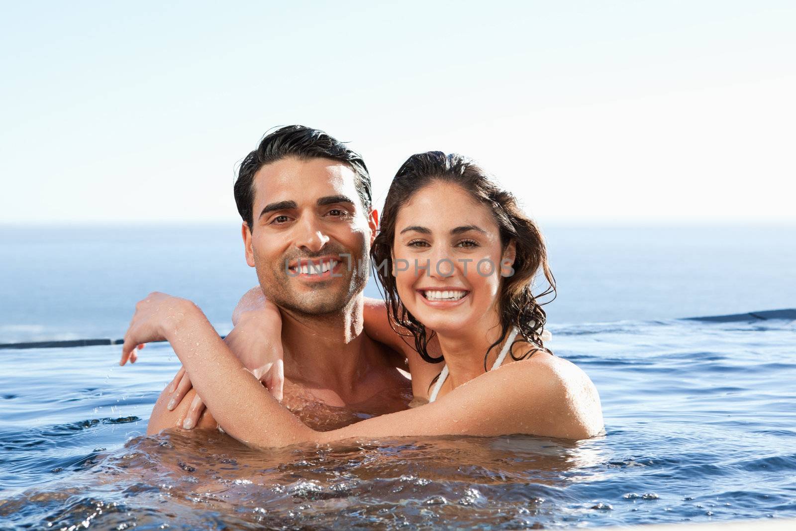 Smiling young couple embracing in the pool