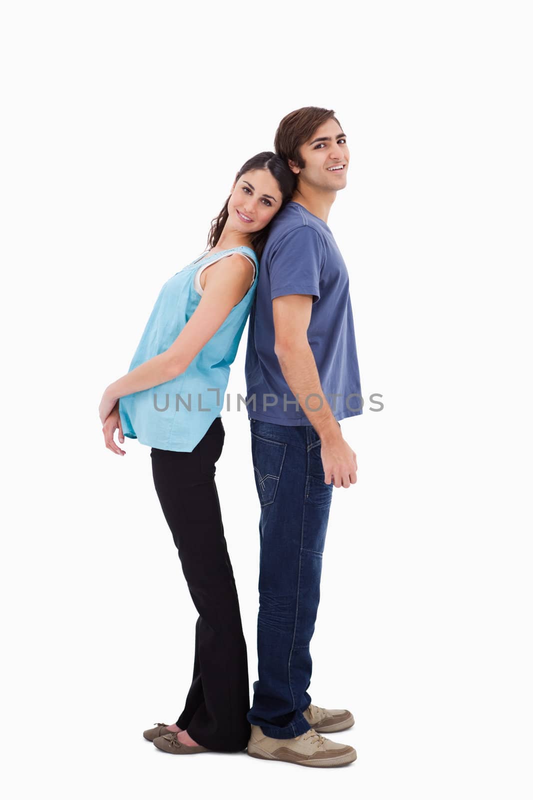 Portrait of a young couple standing back to back against a white background
