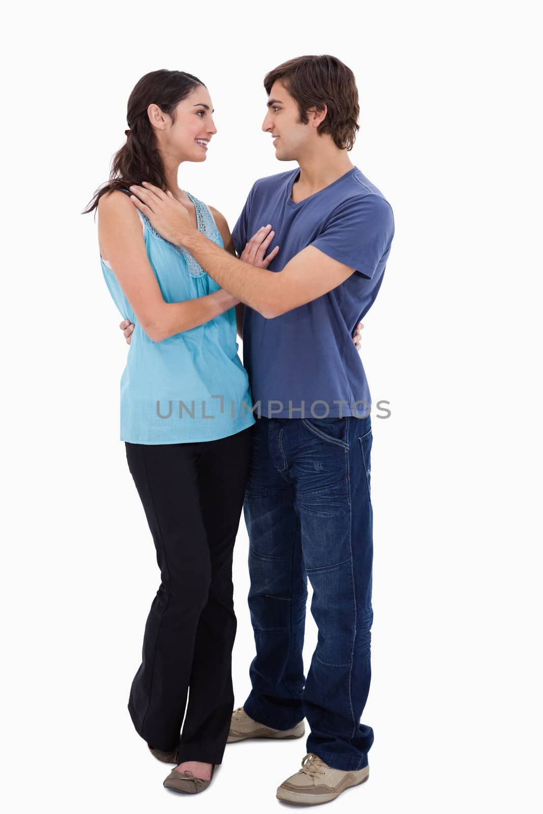 Portrait of a young couple embracing each other against a white background