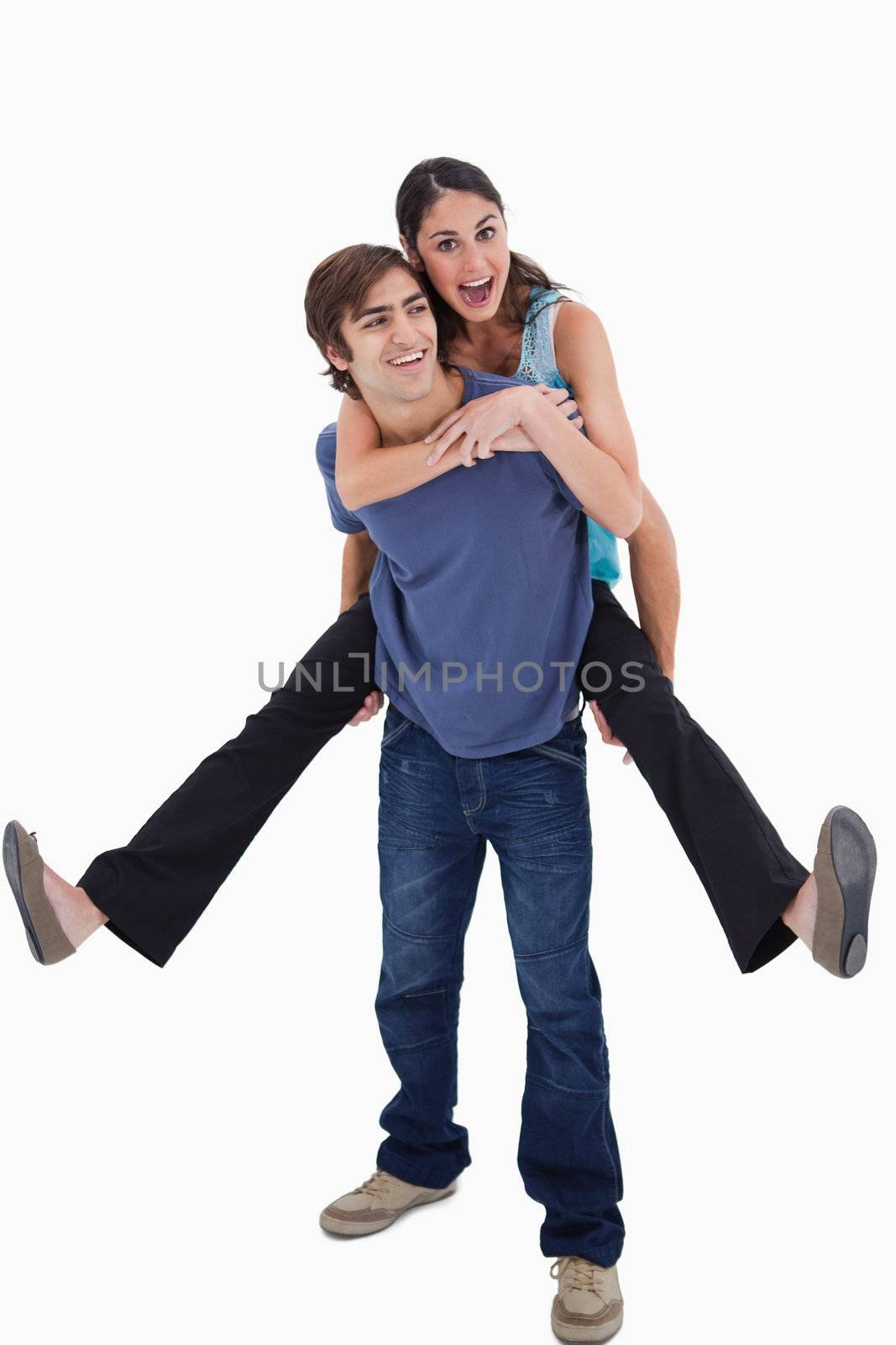 Portrait of man holding his girlfriend on his back against a white background