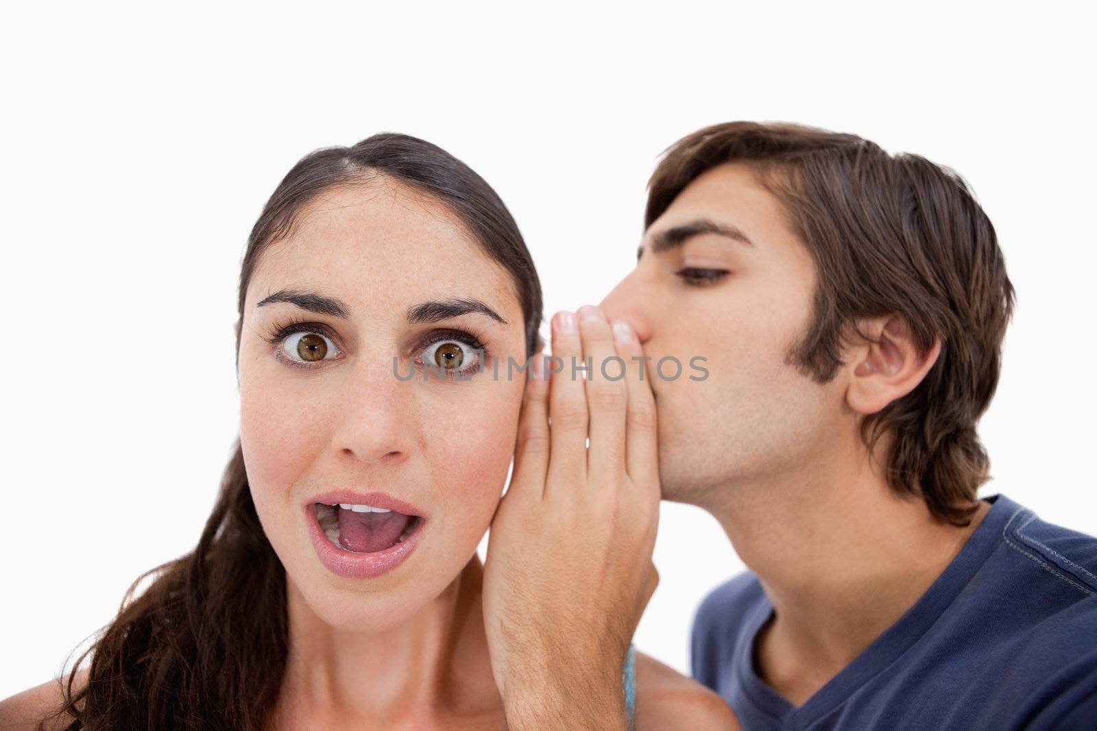 Man whispering something shocking to his fiance against a white background