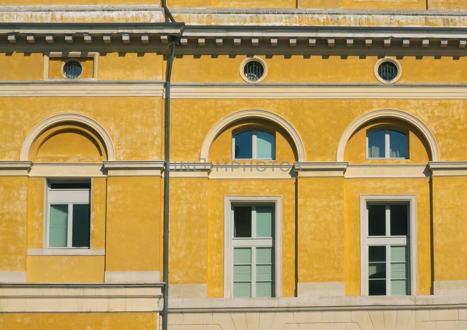 Three windows on the facade of the yellow house in the classical style