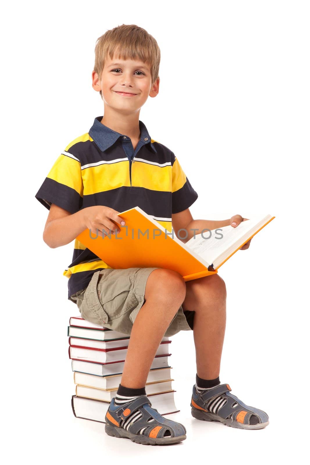 Schoolboy is sitting on books isolated on a white background