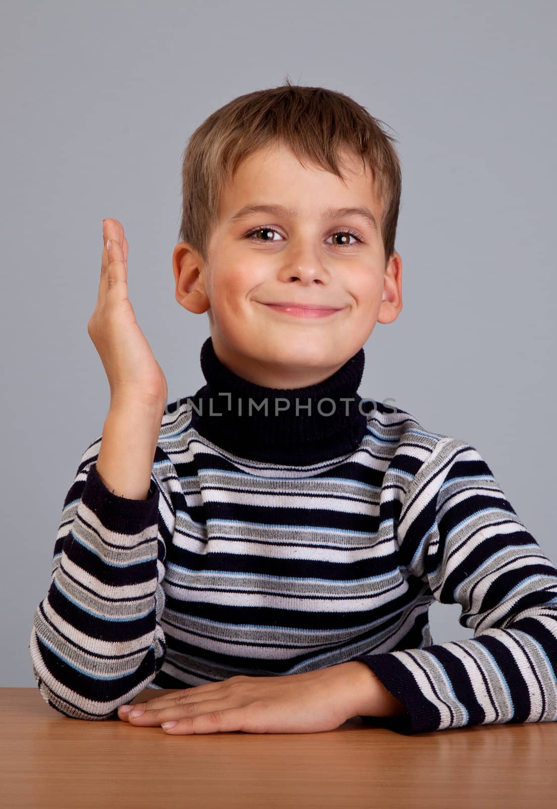 Cheerful Schoolboy ready to answer question isolated on a gray background