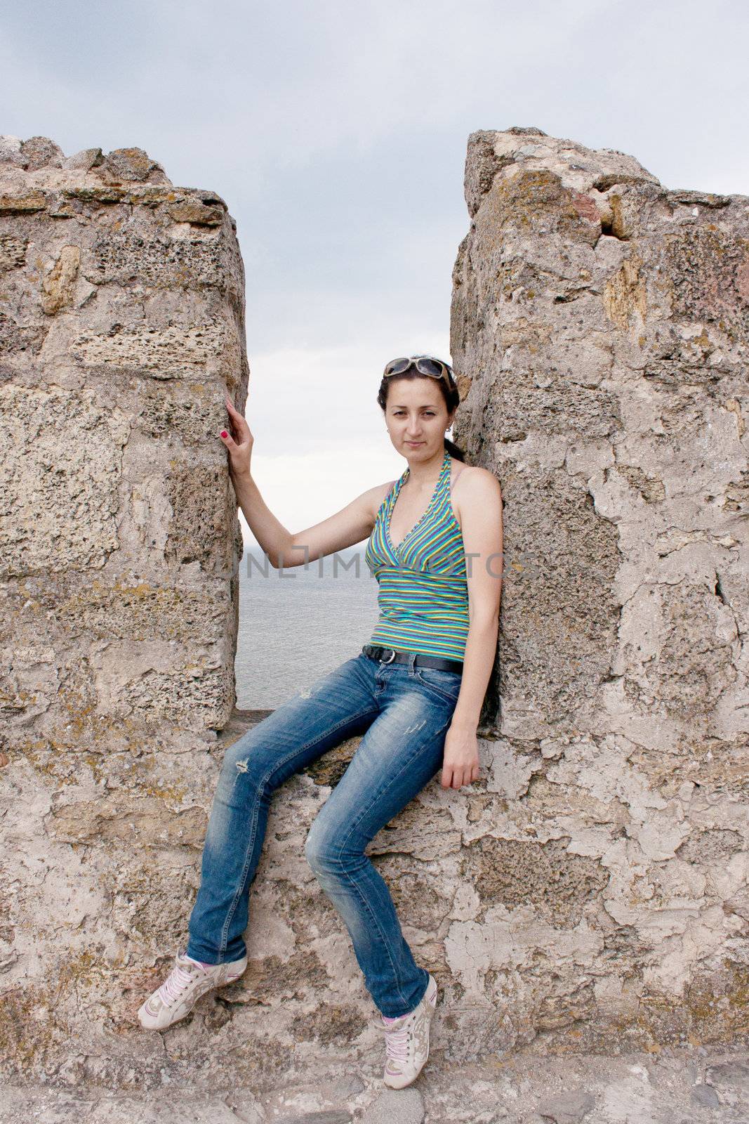 A girl sits in a niche of a stone wall by victosha