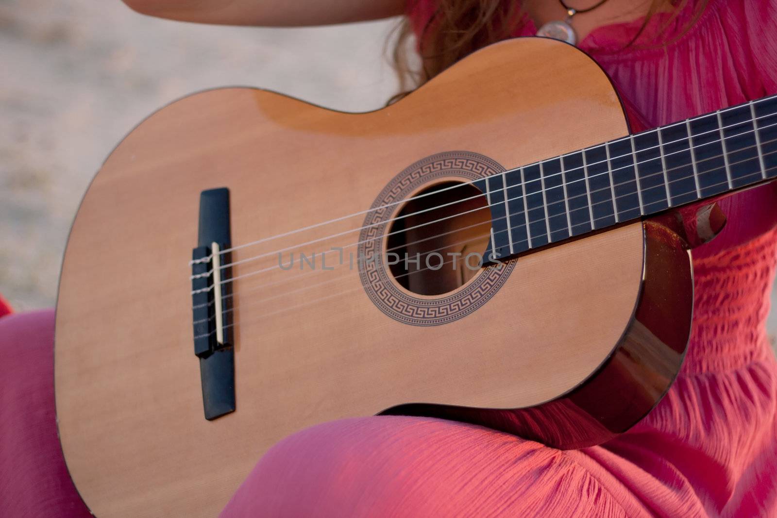 A girl in a dress playing a guitar shot on the nature