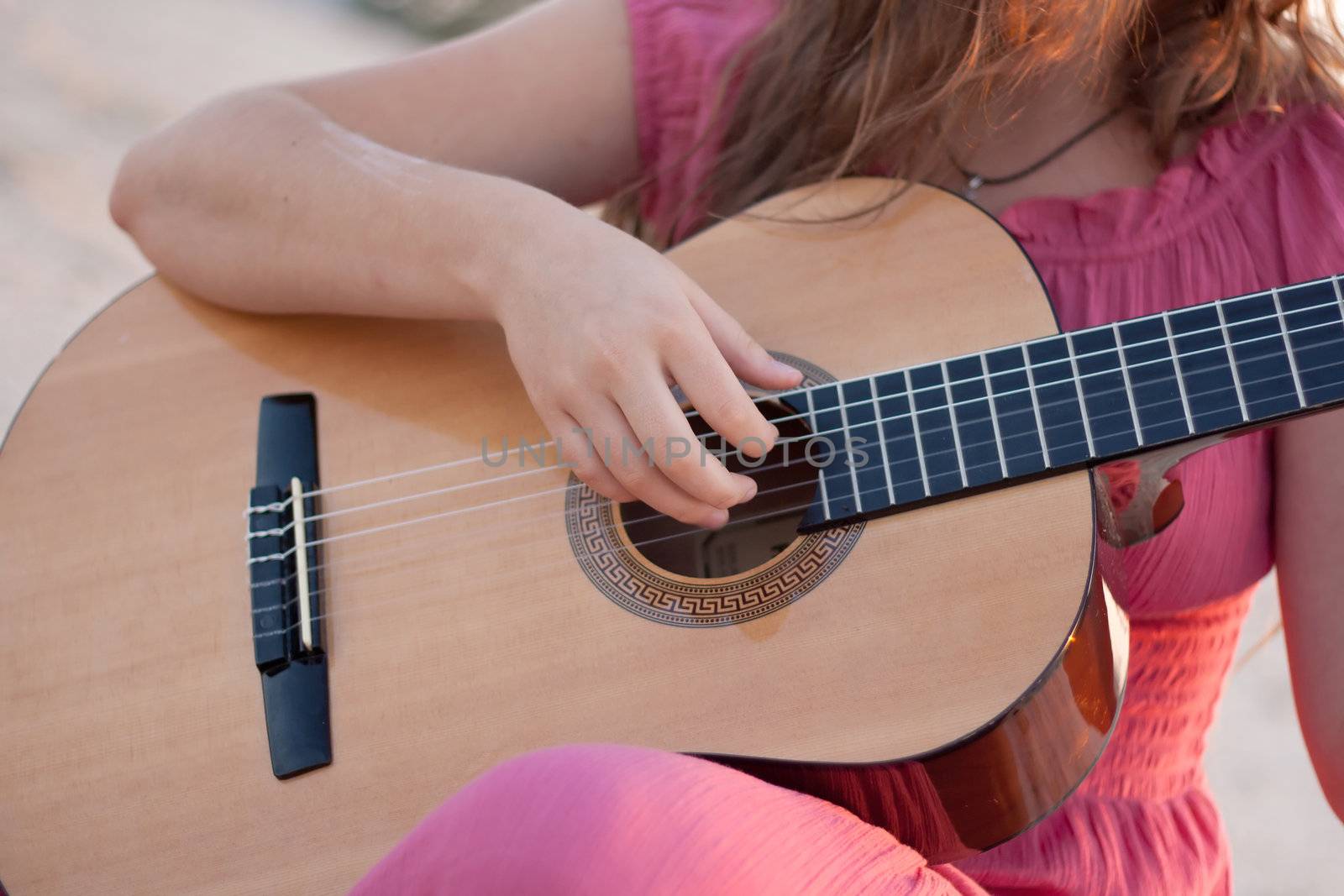 A girl in a dress playing a guitar shot on the nature