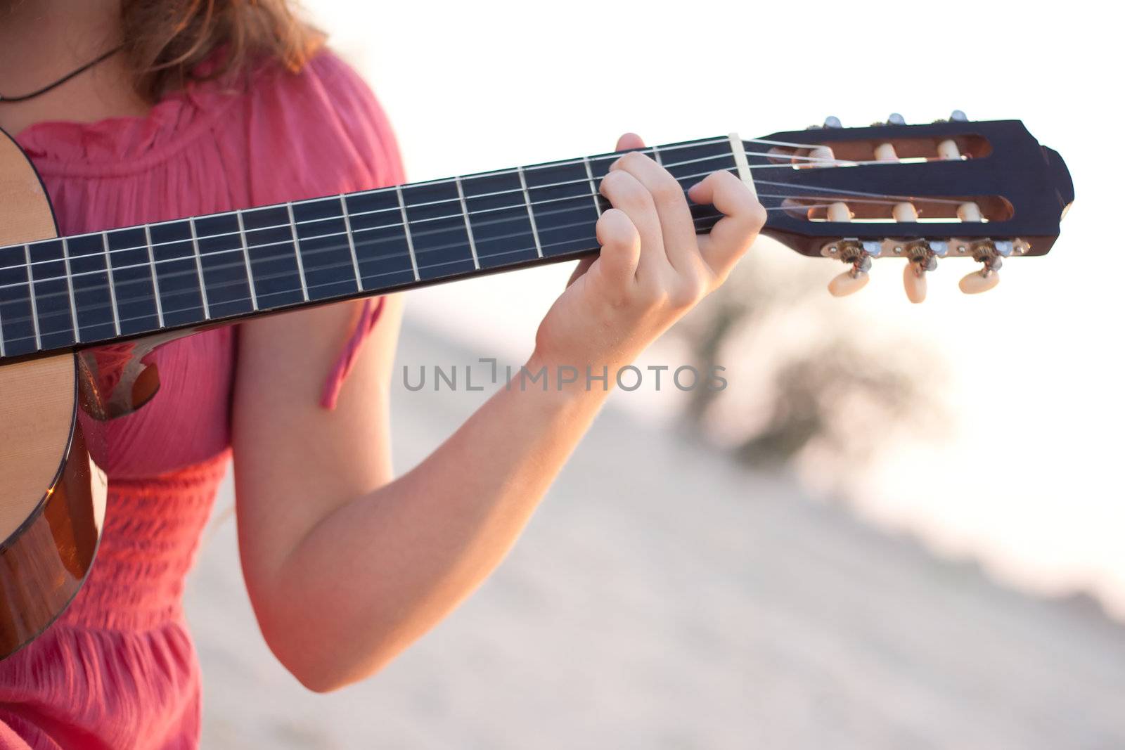 A girl in a dress playing a guitar shot on the nature