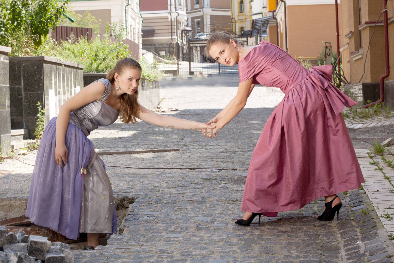 Two girls in beautiful dresses on the stairs shooting outdoors