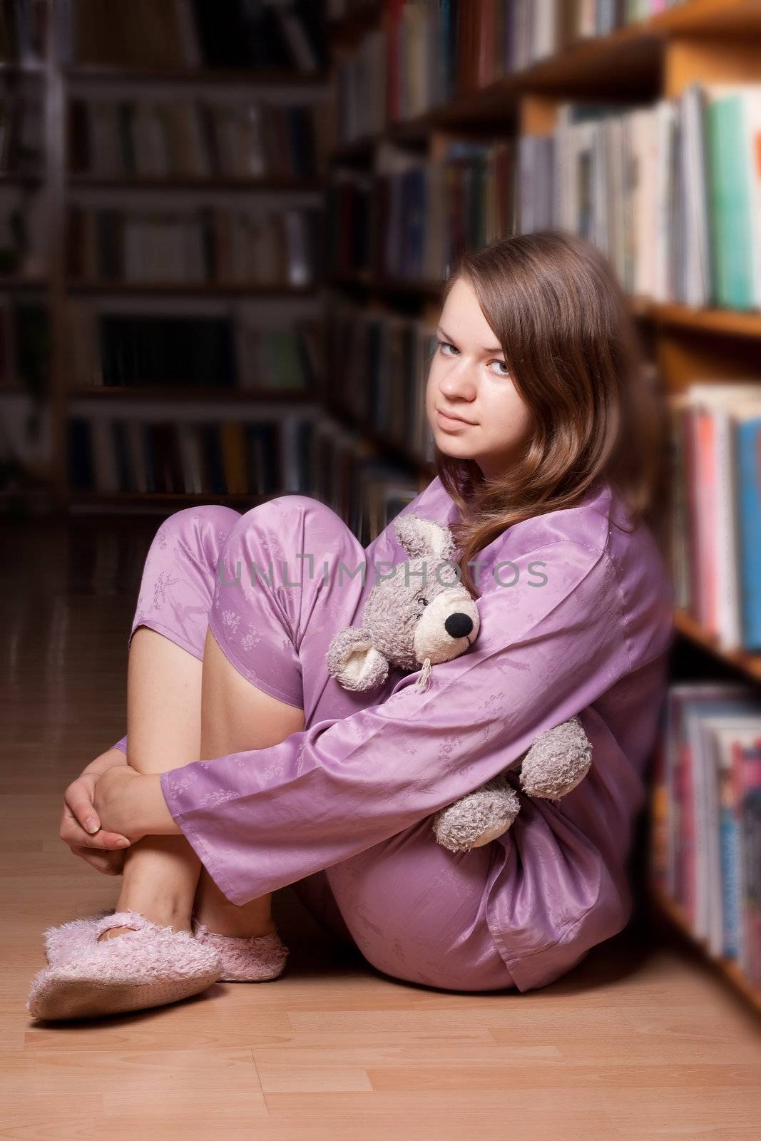 The girl in pink pajamas in the library among the books