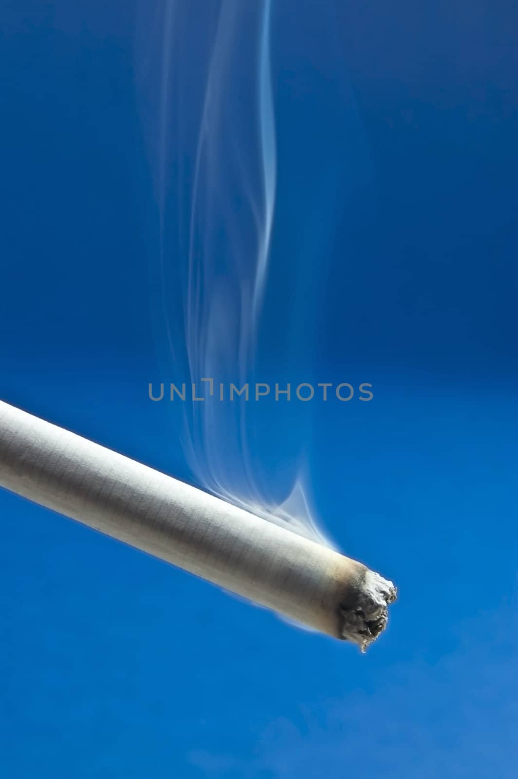 Burning cigarette with smoke on blue background 