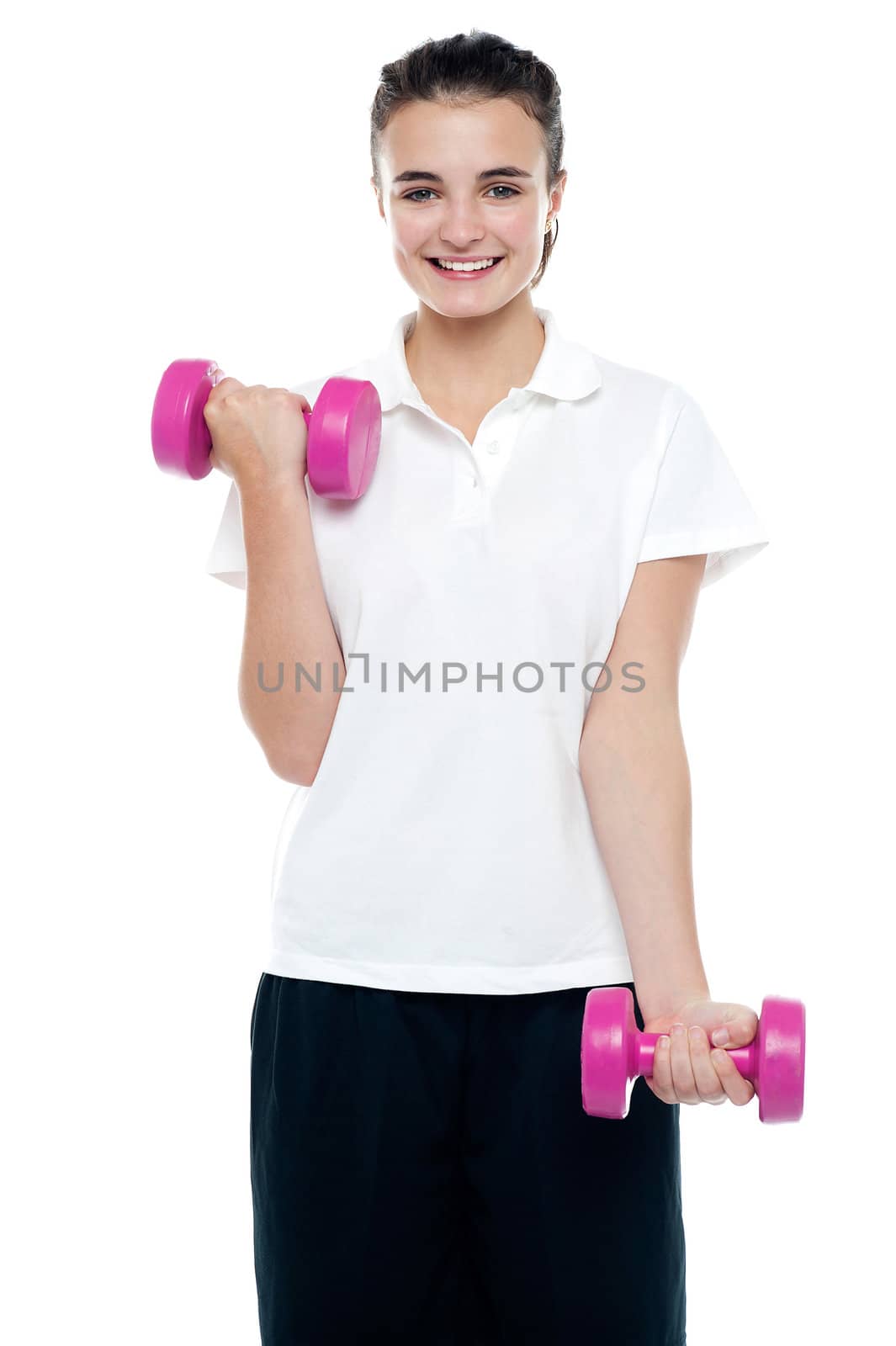 Smiling fitness teenage girl lifting weights. Exercising with pink dumbbells