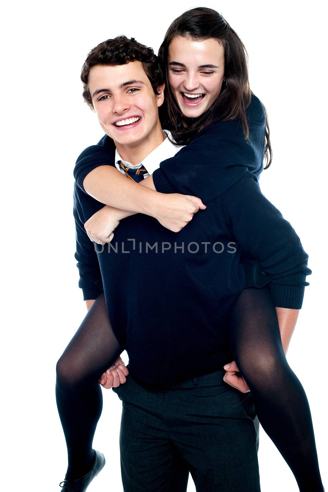 Cheerful boy carrying school friend on his back by stockyimages