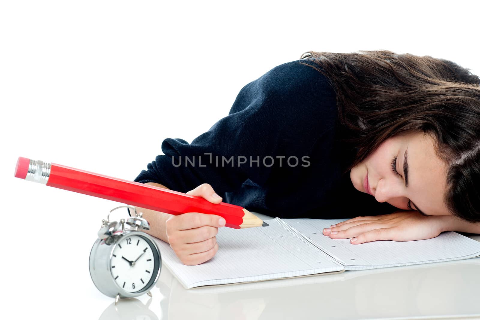 Exhausted schoolgirl dozing off while writing her test paper