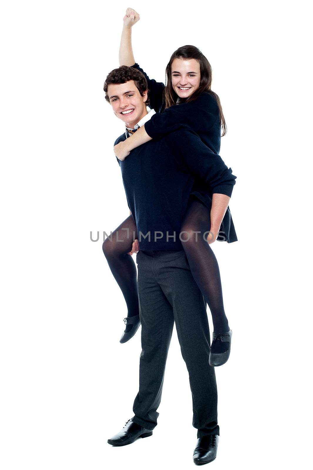 Schoolgirl cheering with raised arm during piggy ride by stockyimages