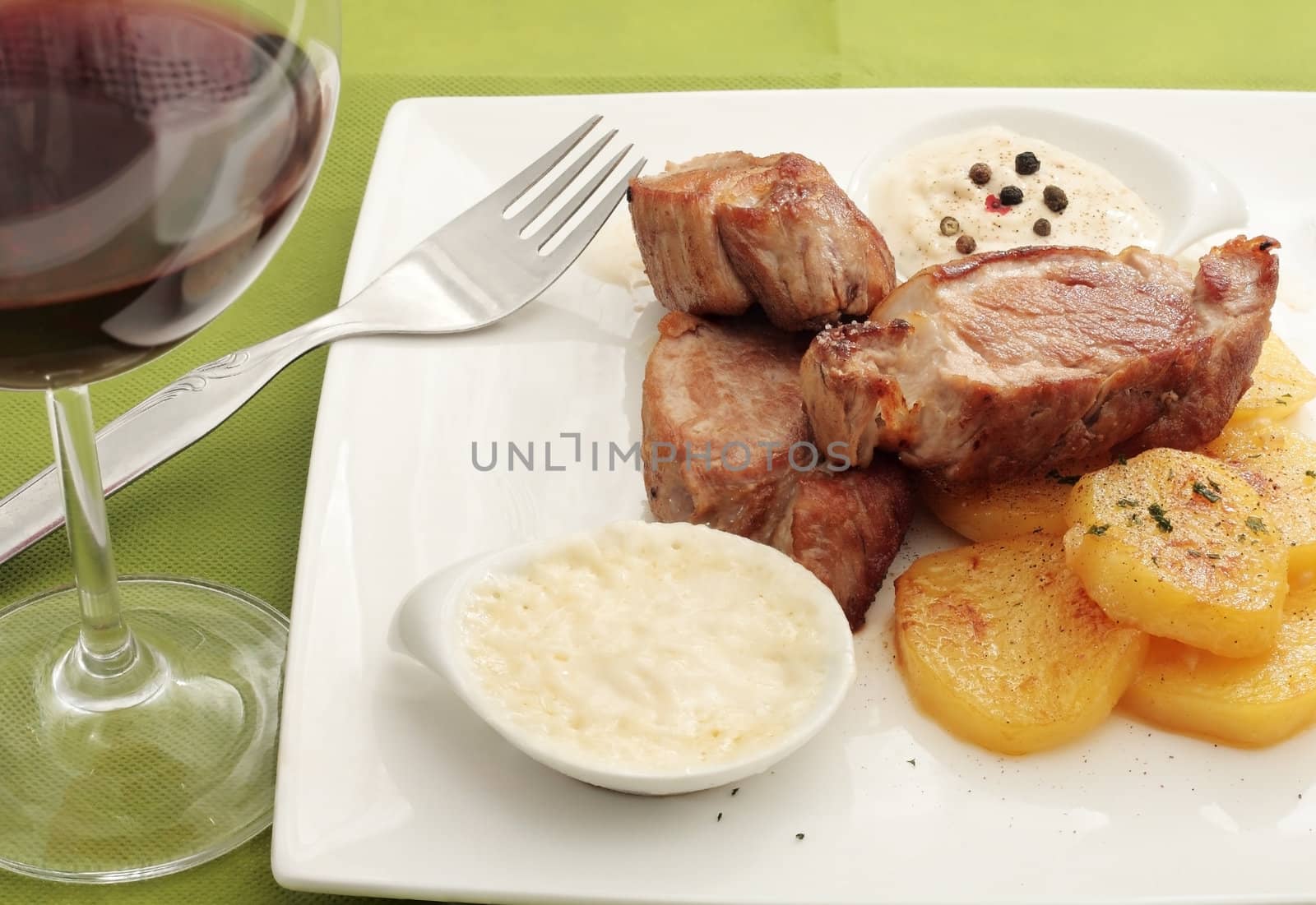 chopped pork sirloin steak with pepper sauce accompanied by potatoes bakers and glass of red wine