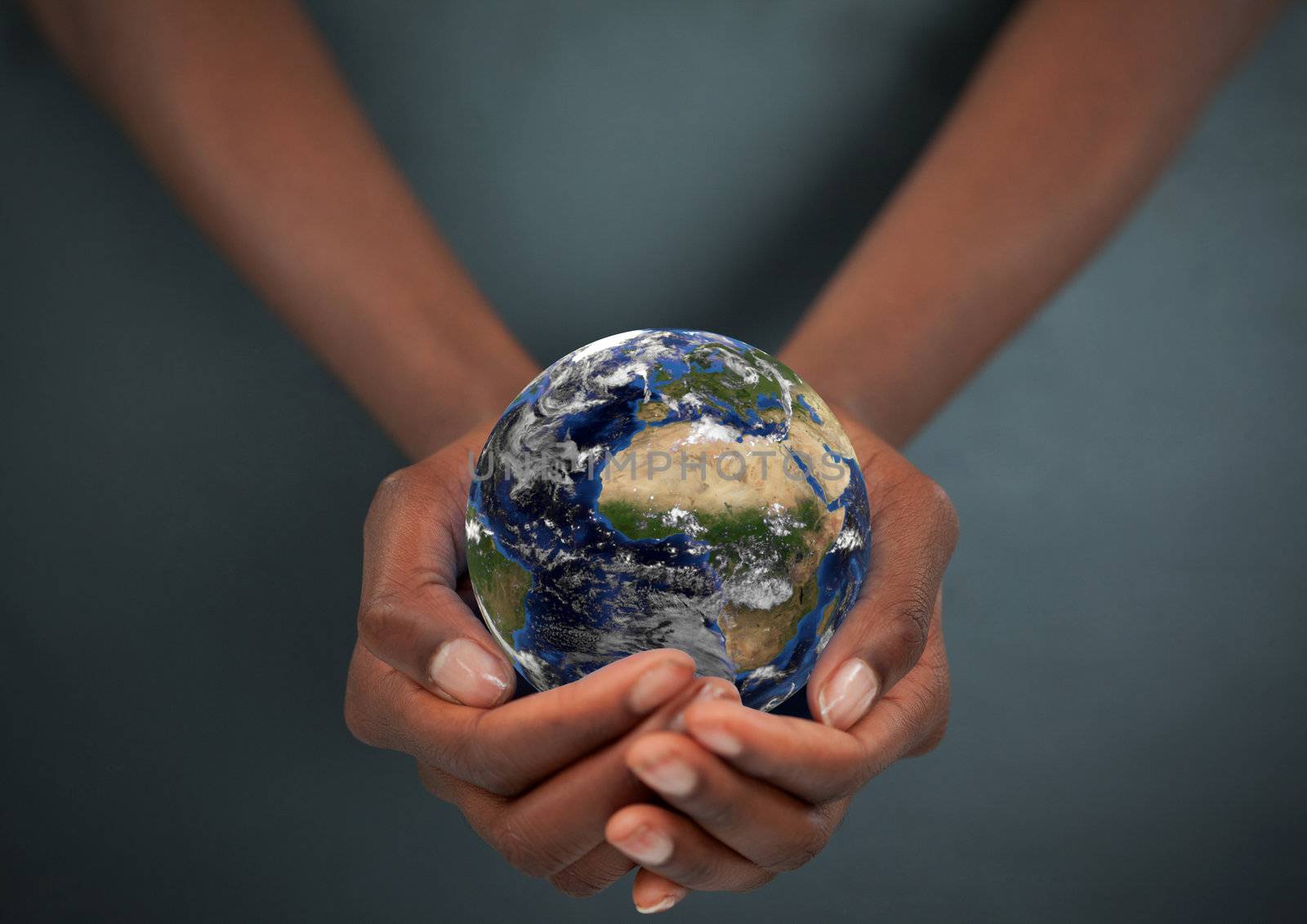 Feminine hands holding the Earth against a dark background