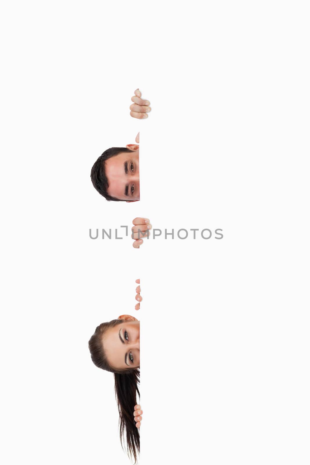 Young business partners looking around the corner against a white background