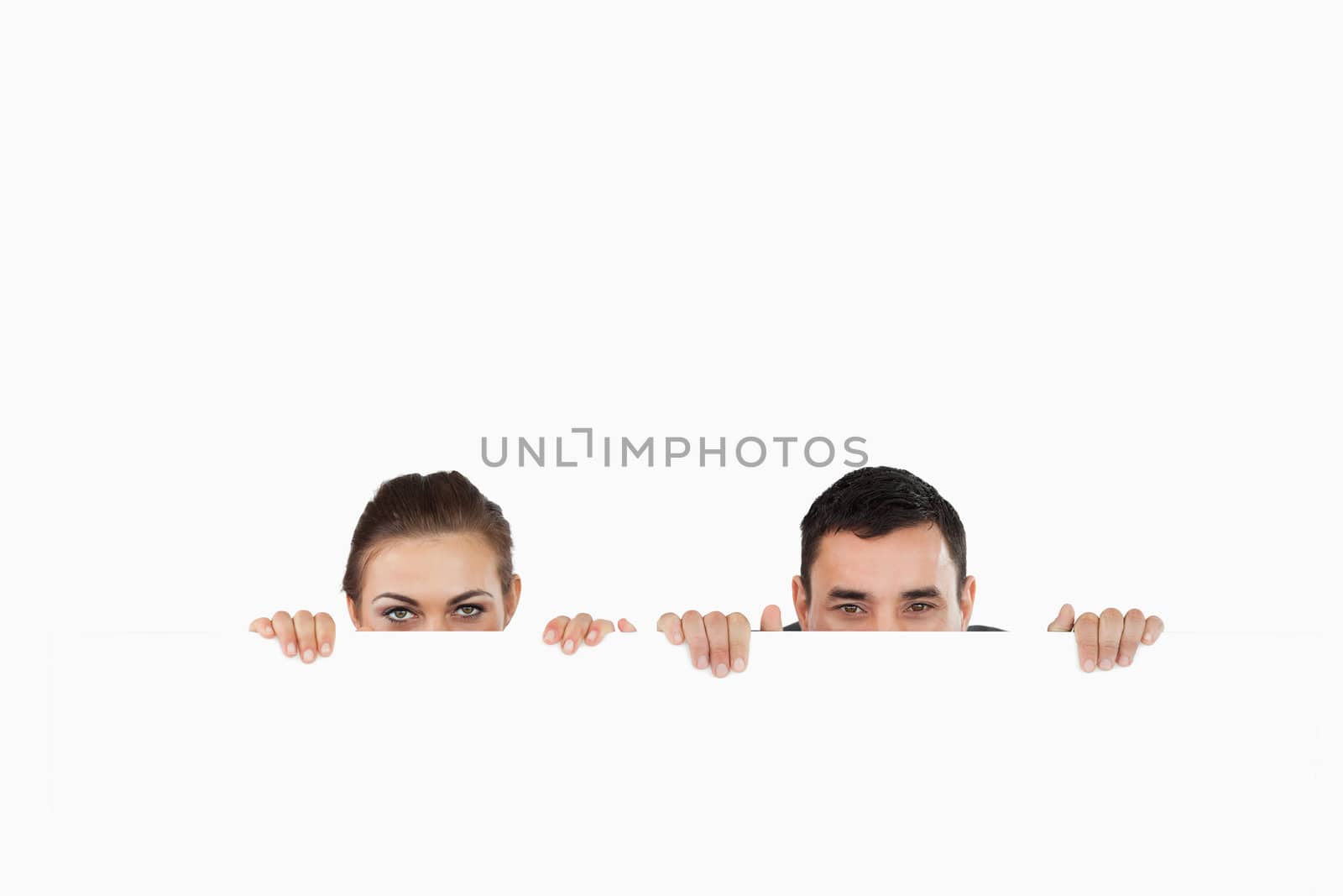 Business partners hiding behind a sign against a white background