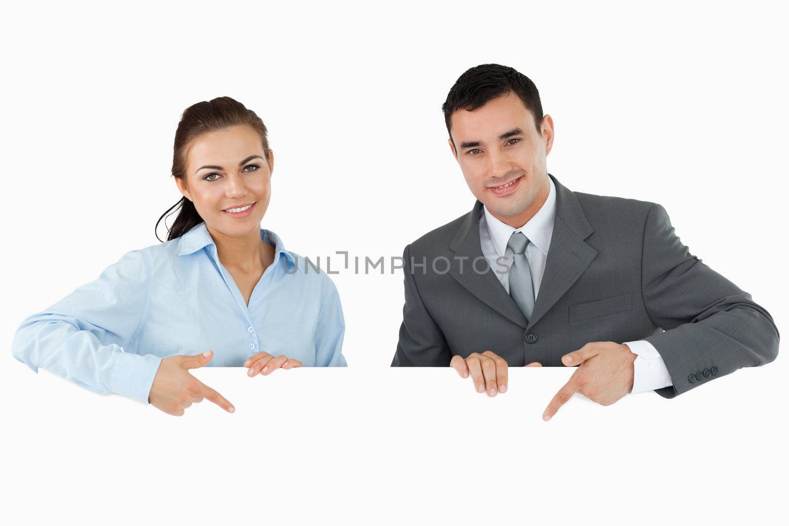 Business partners pointing at sign they are holding against a white background