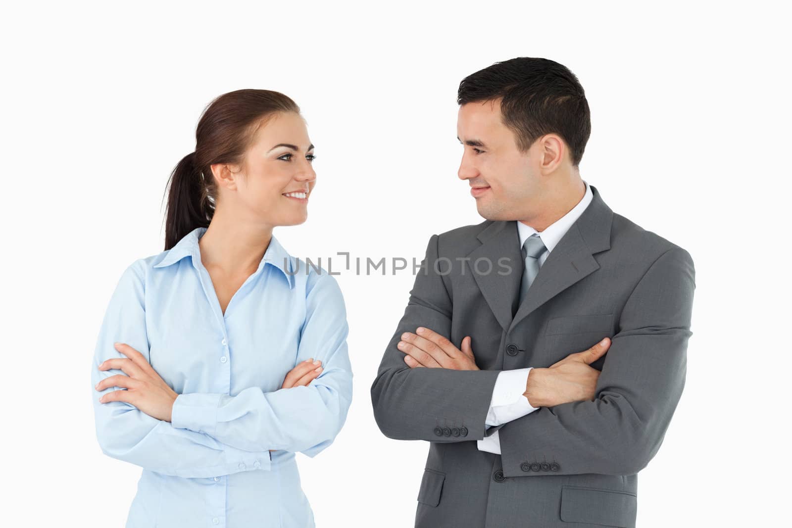Business partners with arms folded looking at each other against a white background