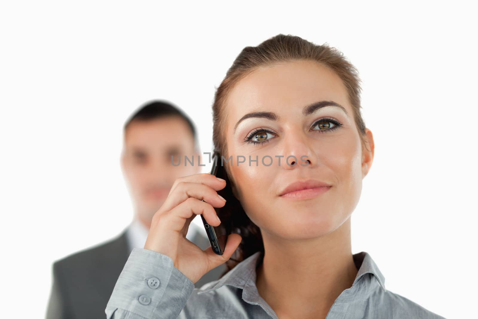 Close up of confident businesswoman on the phone with colleague behind her against a white background