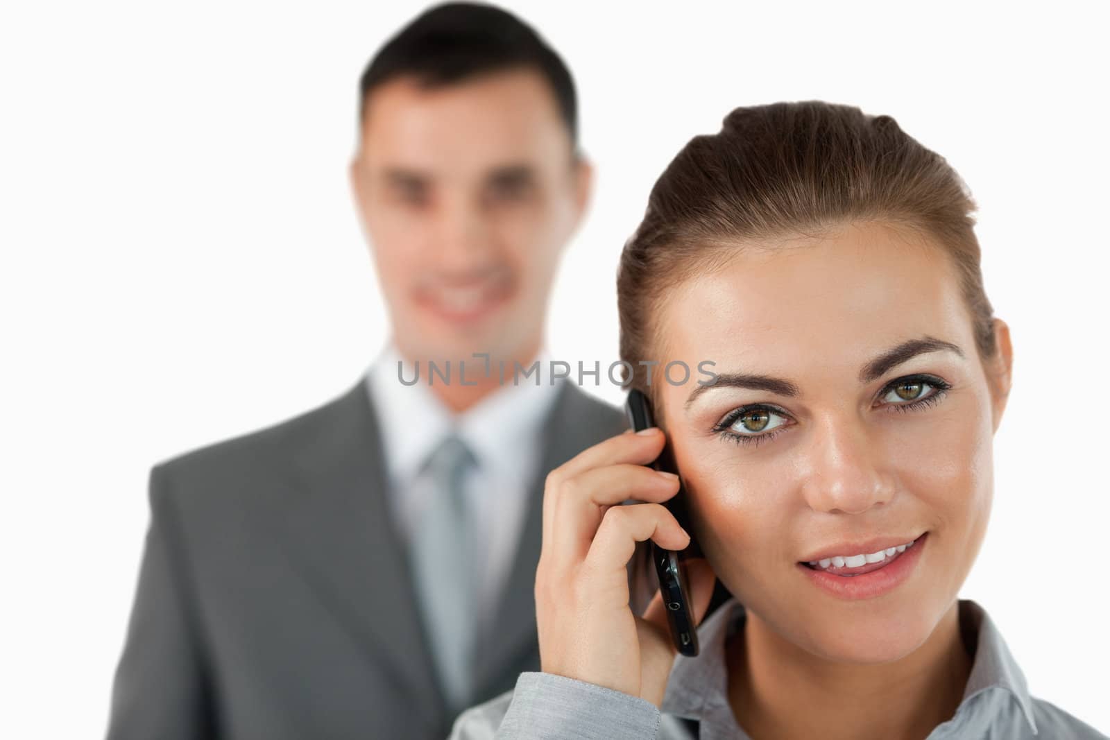 Close up of businesswoman on the phone with colleague behind her against a white background